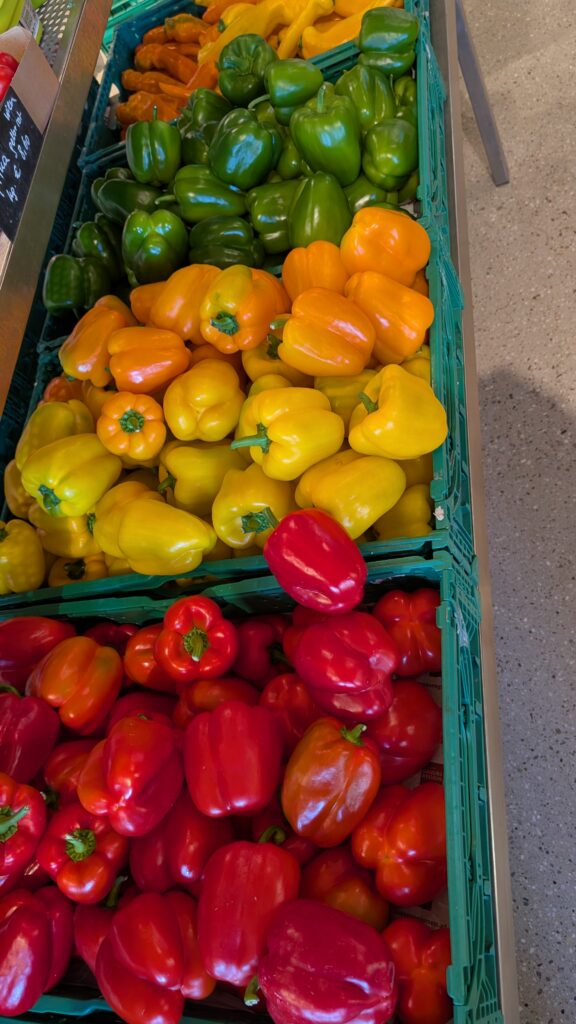 Marktstand mit Kisten voller roter, gelber, oranger und grüner Paprika