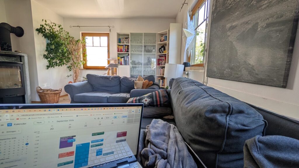 Laptop mit geöffnetem Wochenkalender auf dem Sofa in einem gemütlichen Wohnzimmer